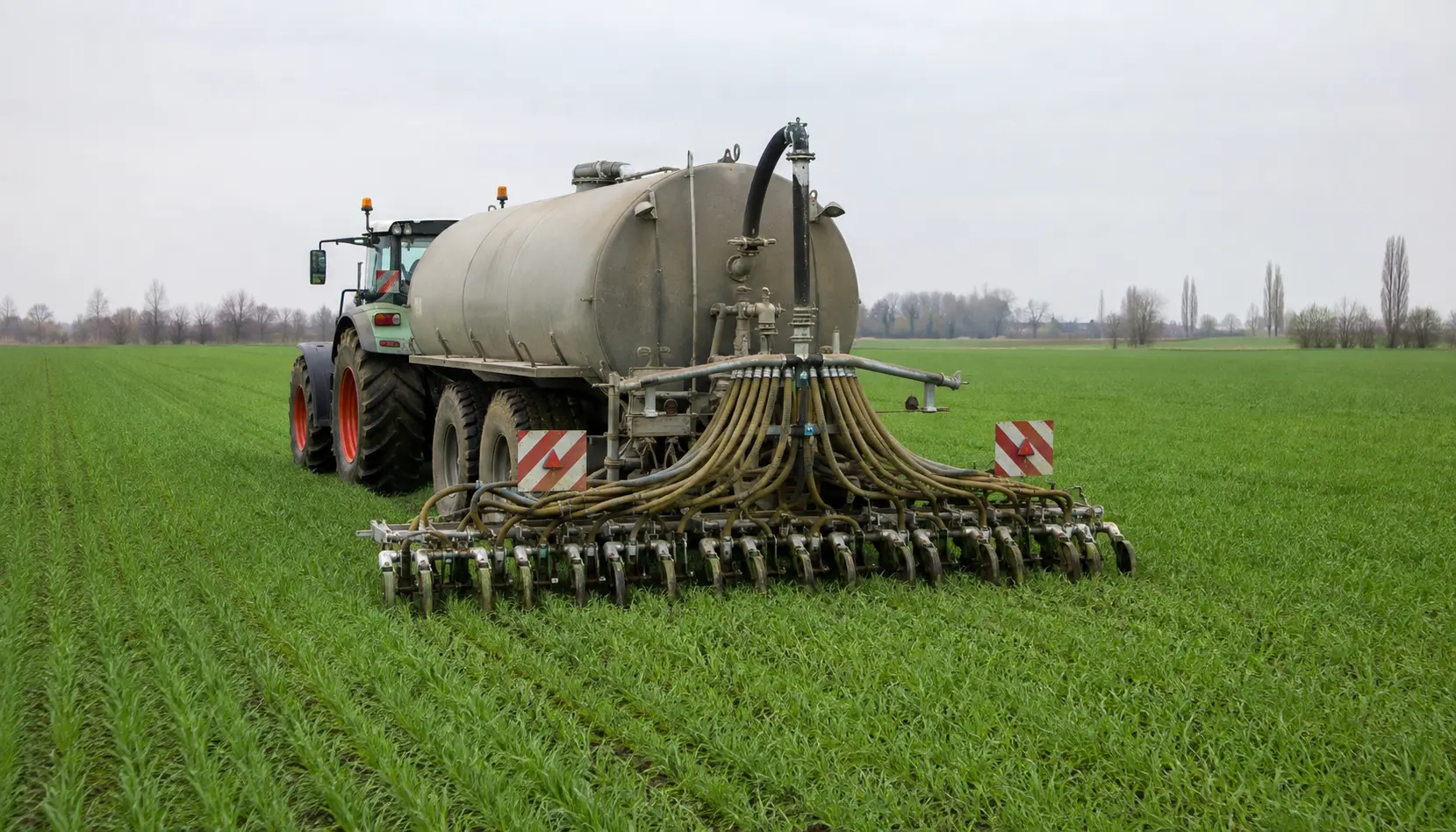 Carro botte distribuisce digestato con sistema a bassa emissione vicino al terreno in un campo coltivato